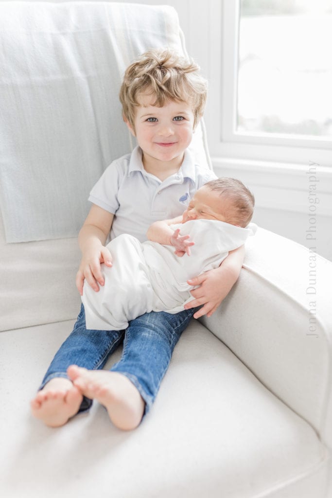 Proud big brother taking a portrait with newborn little brother 