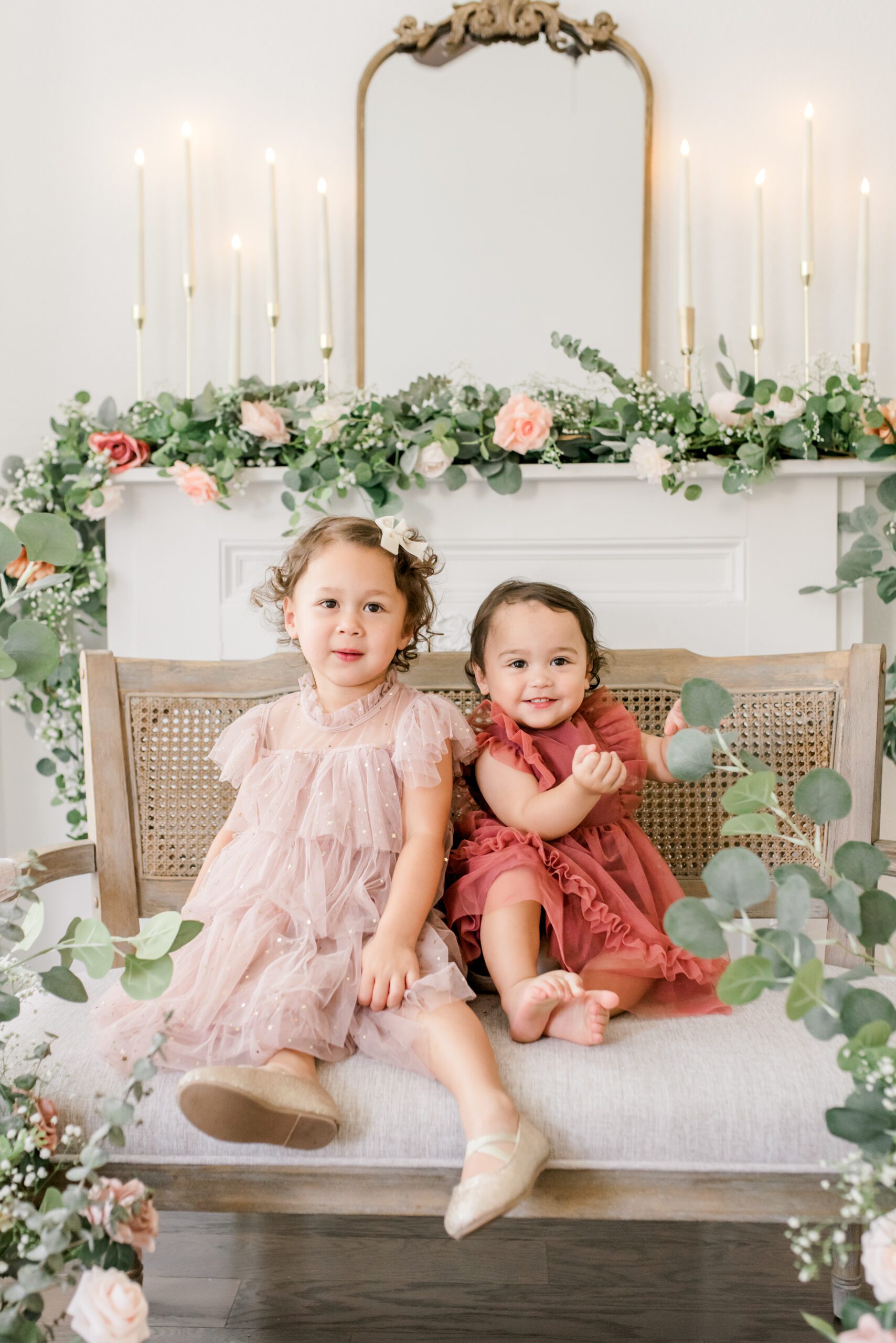 Luxury Houston studio mommy and me portrait session featuring a mother with her two young daughters surrounded by elegant floral arrangements in a soft, light-filled setting