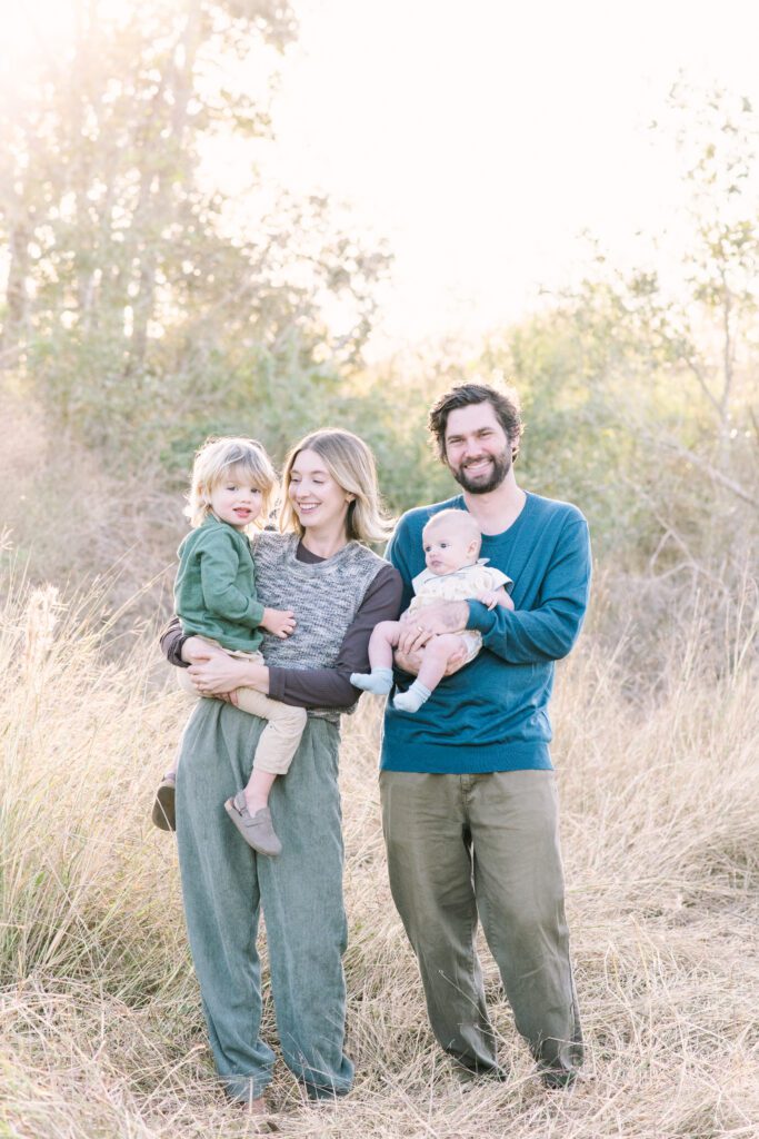Elegant Houston family walking through golden field during fall sunset in League City